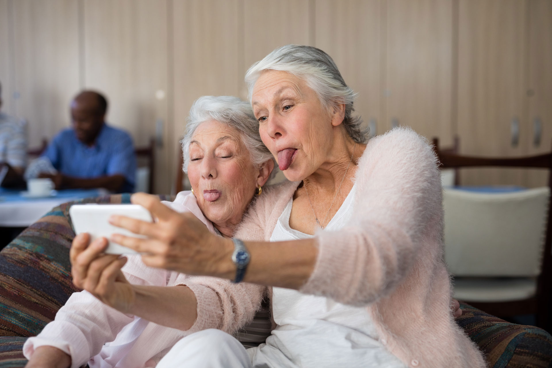 Two senior women taking a selfie and making silly faces together.